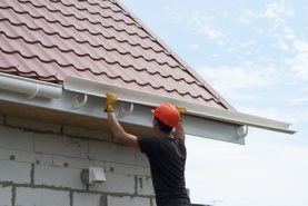 worker installs the gutter system on the roof